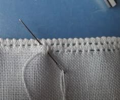 the sewing needle is being used to sew on white material with holes in it