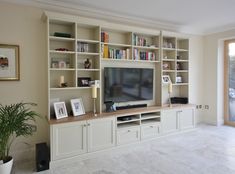 a living room with white bookcases and a flat screen tv