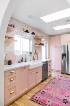 a kitchen with pink cabinets and an area rug