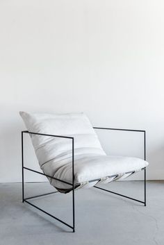 a white chair sitting on top of a cement floor next to a black metal frame