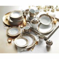 a table topped with lots of white and gold dishes