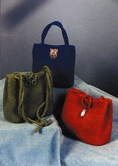 three small purses sitting on top of a blue cloth covered table next to each other