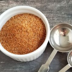 there are three spoons next to a bowl with some food in it on the table