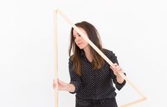 a woman holding a wooden triangle with her hands