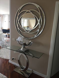 a glass table with a mirror on it in front of a wall mounted art piece