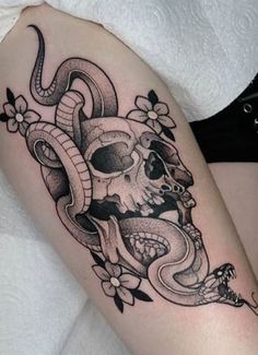 a woman's thigh with a skull and snake tattoo on it