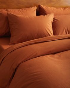 a bed with orange sheets and pillows on it