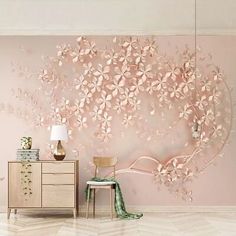 a pink wall with flowers painted on it and a chair in front of the dresser