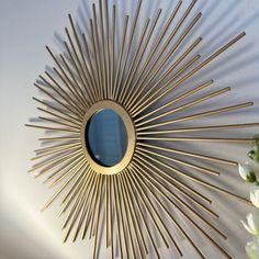 a sunburst mirror on the wall with flowers in vases next to it