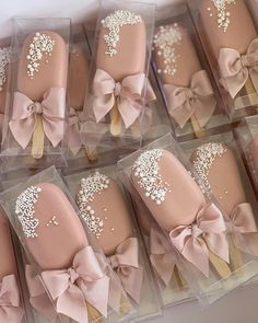 there are many pink and gold decorated cookies in plastic boxes with bows on them,