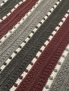 a crocheted rug with red, grey and white stripes on the bottom is shown