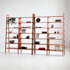 a book shelf with books and other items on it in front of a white wall