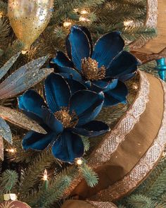 a christmas tree decorated with blue flowers and gold ribbons