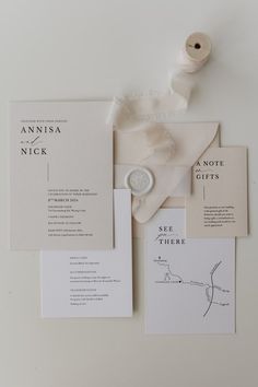 the wedding stationery is laid out on top of each other, including a white ribbon