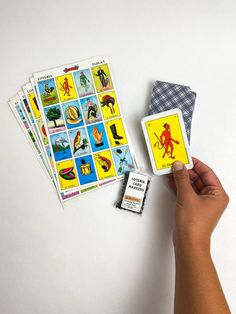 a hand holding a deck of cards next to some stickers on a white surface