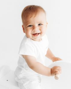 a baby is smiling while holding a white object