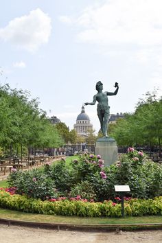 a statue in the middle of a flower garden