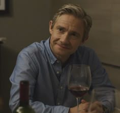 a man sitting at a table with a glass of wine