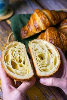 two croissants being held in front of each other on a wooden table