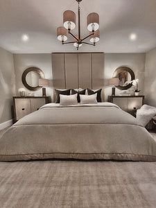 a large bed sitting inside of a bedroom next to two nightstands and a chandelier