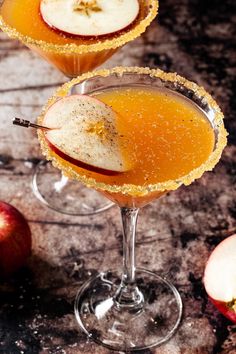 two glasses filled with apple cider on top of a table