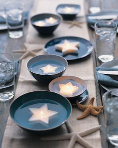 the table is set with blue plates and star shaped candles