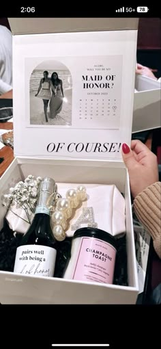 a woman holding a bottle of wine next to a box with personalized items in it