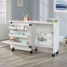 a sewing machine sits on wheels in front of a white table with two storage shelves