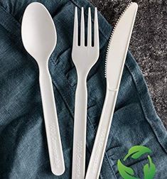 two white plastic utensils sitting next to each other on top of denim pants