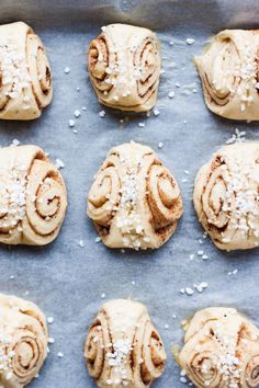 twelve cinnamon rolls on a baking sheet with sea salt sprinkled on top, ready to go into the oven