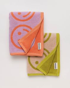 two towels and one towel folded up on top of each other with an orange, purple, and green design