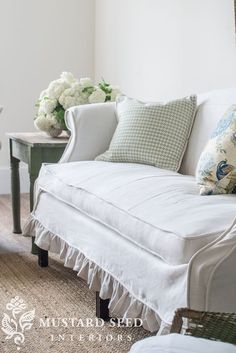 a white couch sitting next to a table with flowers on it