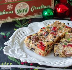 three pieces of fruit and nut bars on a white plate with christmas decorations in the background