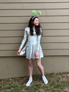 a girl in a dress with two green pom - poms on her head