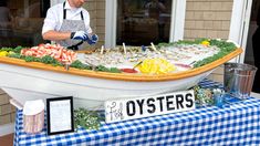 a man standing in front of a boat filled with oysters and other food items