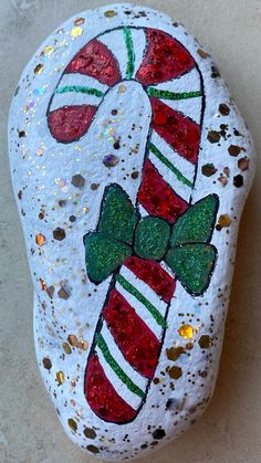 a painted rock with a candy cane on it's side and sequins