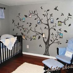 a baby's room with a tree painted on the wall and pictures hanging from it