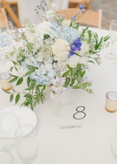 a bouquet of flowers is sitting on the table with candles and place cards in front of it