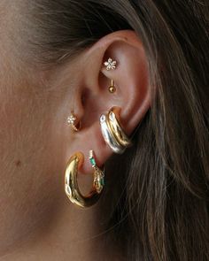 a close up of a person wearing two different types of ear piercings on their ears