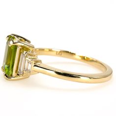 Peridot is the much beloved birthstone of August and a favorite stone of ours. One of the few gemstones that's always the same color—green—most of the world's peridot came to the earth's surface by way of a volcano! This ring holds a 1.40 carat emerald cut peridot that's accented by two pairs of graduated lab grown diamond baguettes. A modern interpretation of an age-old design, we imagine this ring as a nontraditional engagement piece but it's pretty enough for any occasion! Metal: 10K Yellow Gold Main Stone: 1 Emerald Cut Peridot (1.40 carats, 8 x 6 mm) Accent Stones: 4 Baguette Cut Lab Grown Diamonds (0.19 carat total, G-H color, VS clarity, 4.5 x 1.5 mm & 2.5 x 1.5 mm) Ring Size: 7.0 (can be sized) Peridot Engagement Rings, Chevron Earrings, Jewelry Appraisal, Gemstone Engagement, Peridot Ring, Silver Jewelry Fashion, Jewelry Rings Diamond, Radiant Cut, Jewelry Repair