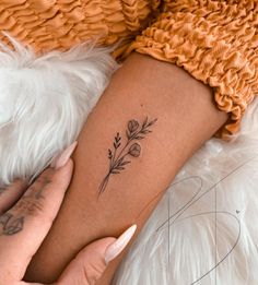 a woman's arm with a small flower tattoo on the left side of her leg