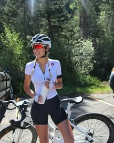 a woman standing next to her bike in the road