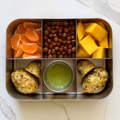 a metal tray filled with different types of food next to oranges and other foods