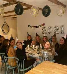 a group of women sitting around a table at a party with balloons and confetti