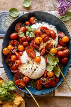 a blue bowl filled with tomatoes and mozzarella