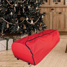 a large red bag sitting in front of a christmas tree