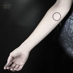 a woman's arm with a small black dot tattoo on the left inner arm