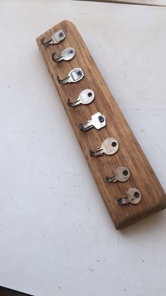 a wooden board that has some metal spoons on it and several keys in the middle