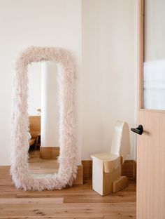 a mirror sitting on top of a wooden floor next to a cardboard box and chair