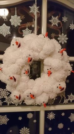 a snowman wreath hanging on the side of a building with snowflakes around it